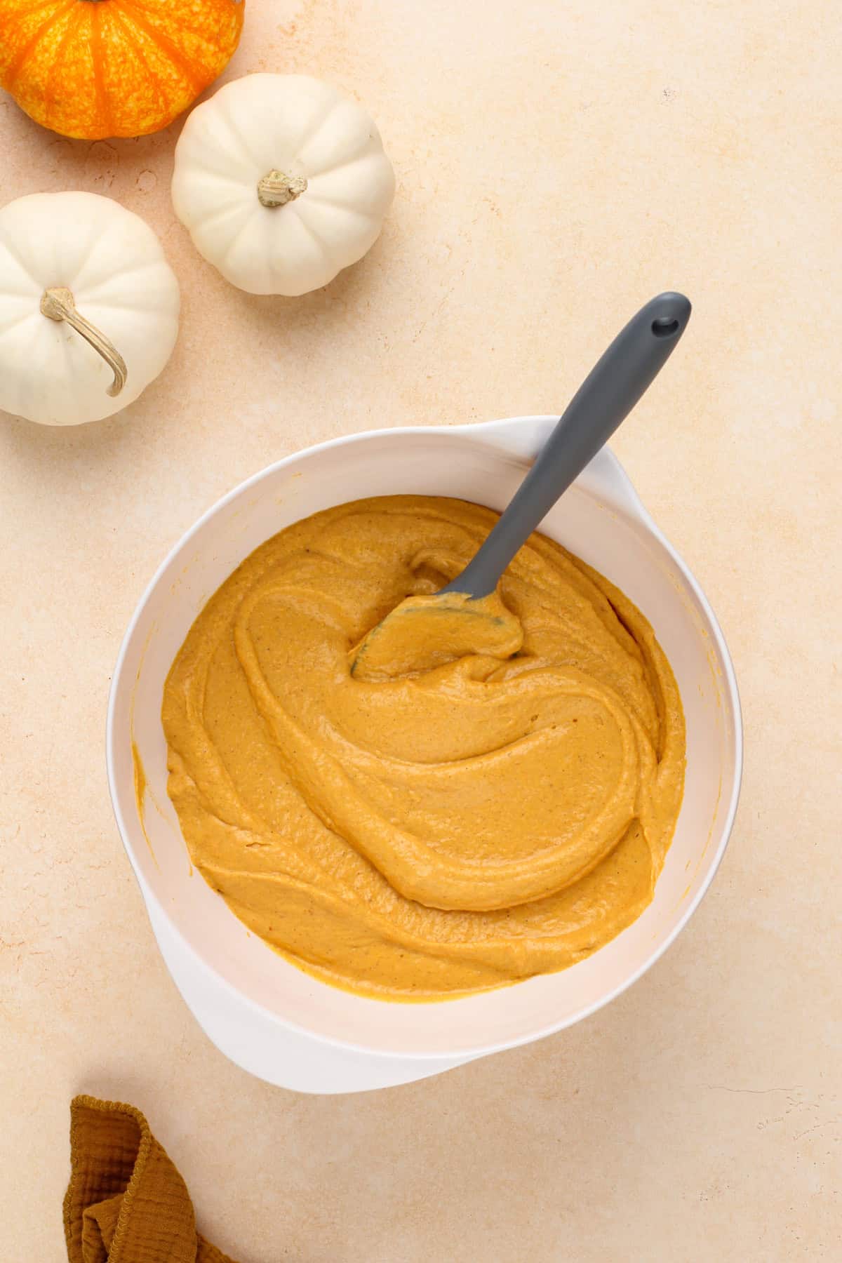 Pumpkin and cream cheese mixture being mixed in a white bowl.