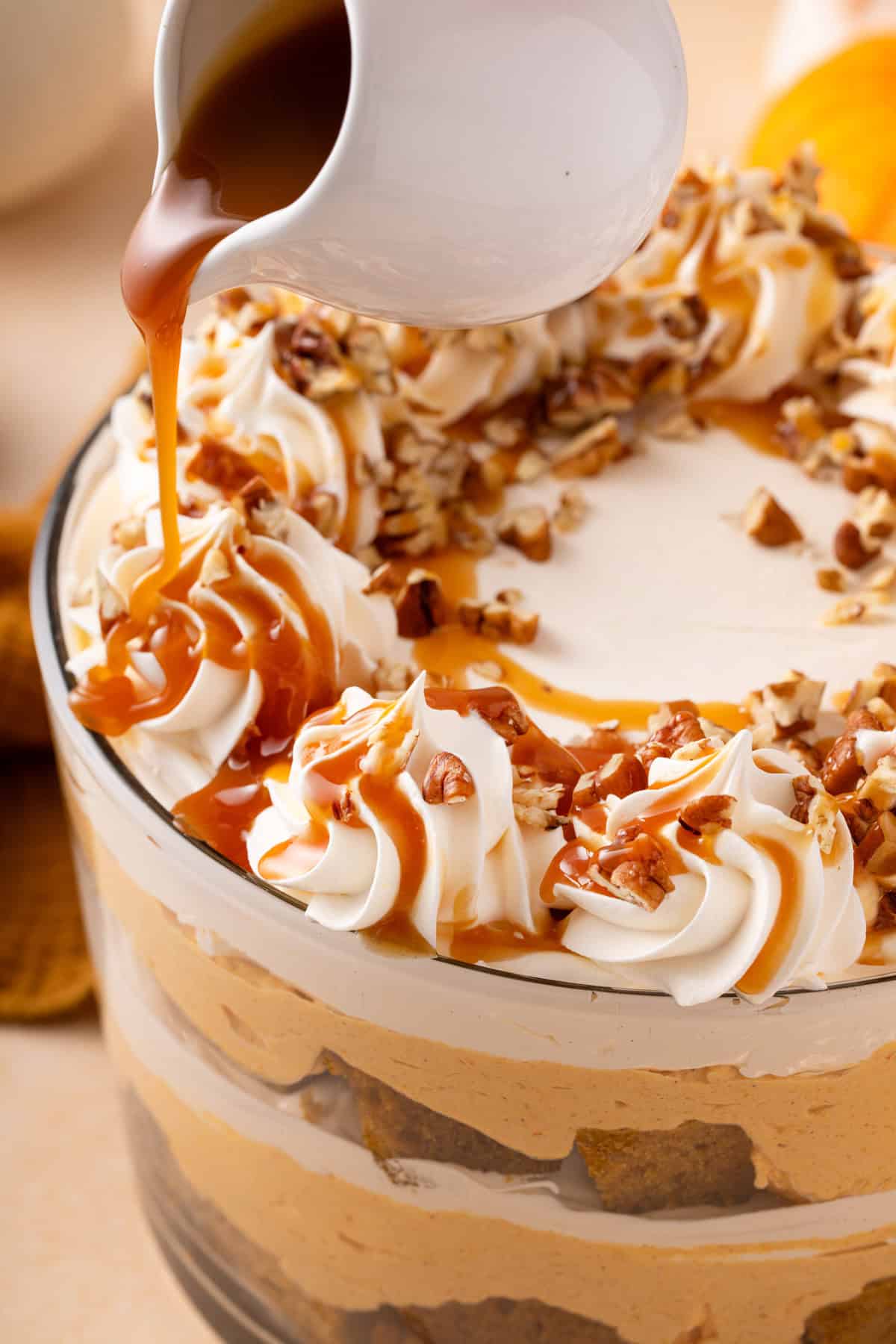 Caramel sauce being drizzled over an assembled pumpkin trifle.