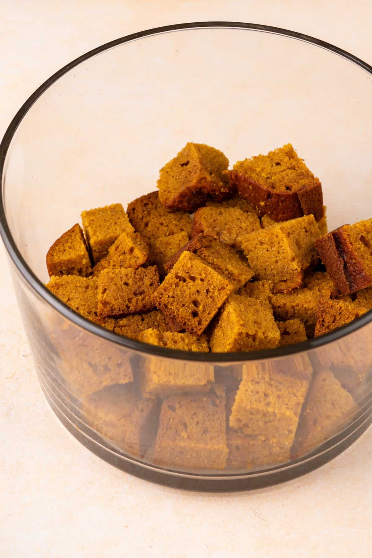 Cubes of pumpkin bread in the bottom of a trifle dish.