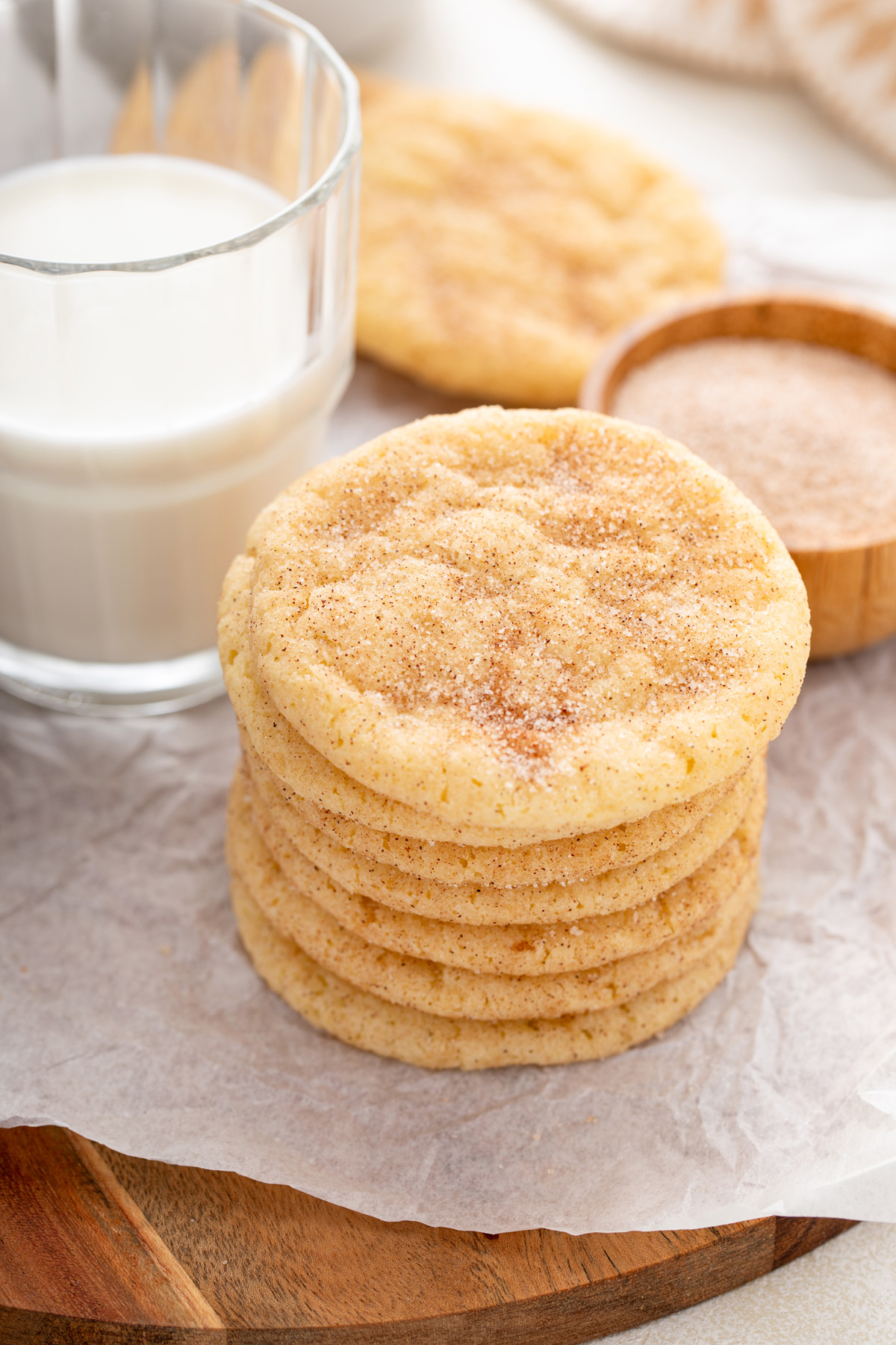 Seven snickerdoodle cookies stacked next to a glass of milk.