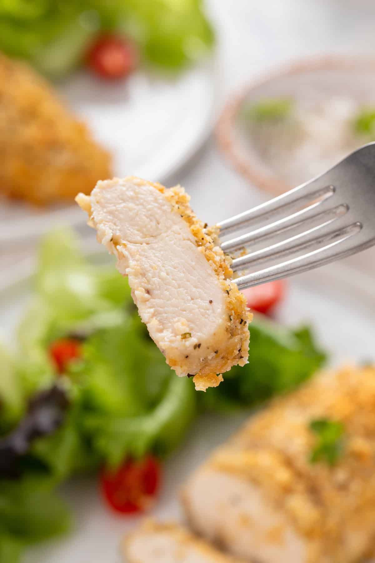 Fork holding up a bite of ritz cracker chicken to the camera.