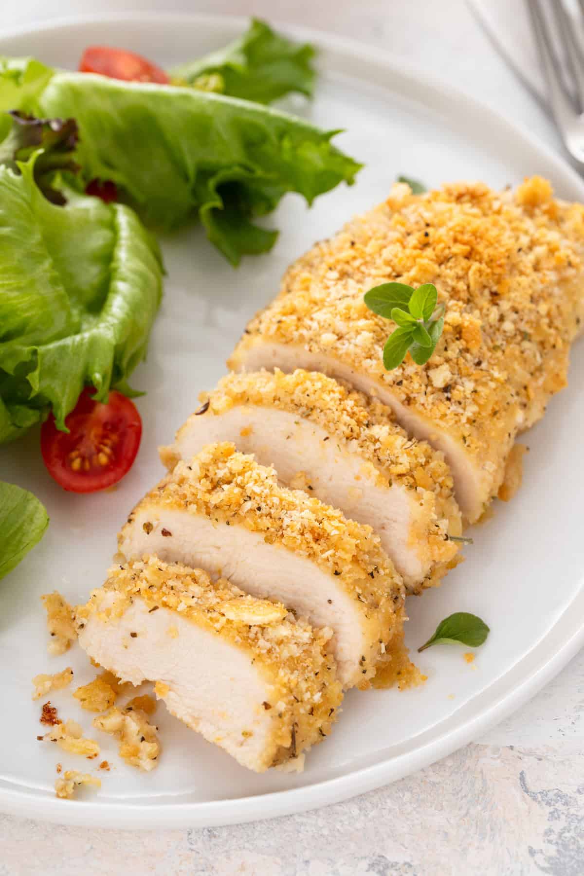 Close up of sliced ritz cracker chicken on a white plate.