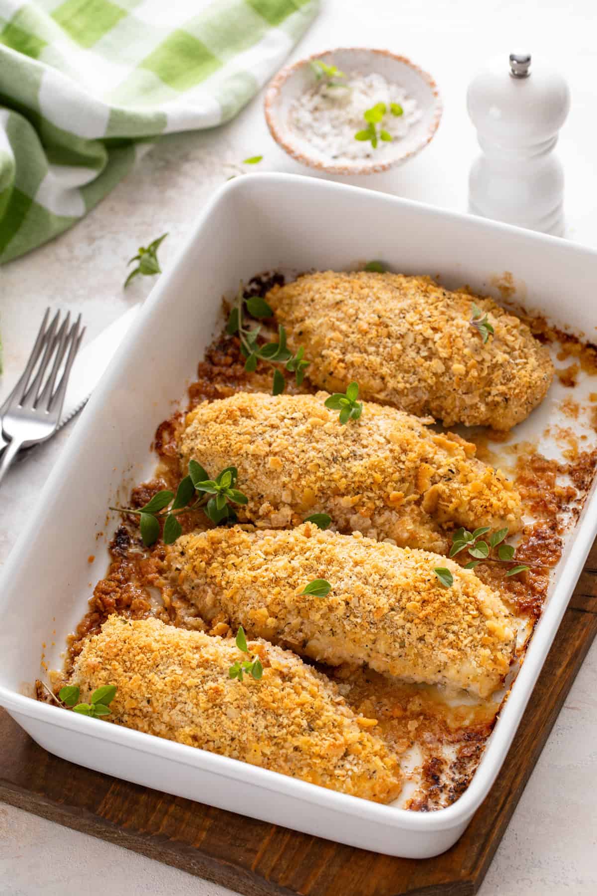 Baked ritz cracker chicken in a white baking dish set on a trivet.