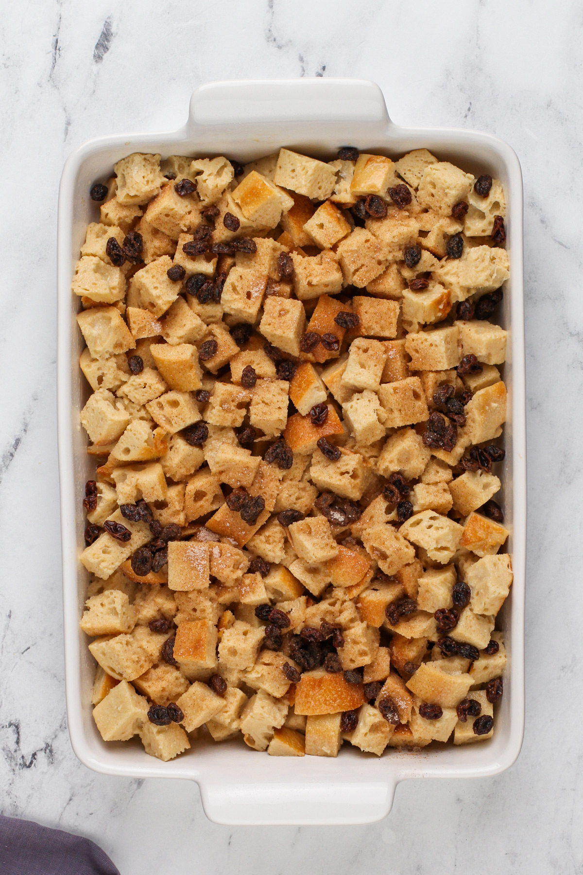 Unbaked irish bread pudding assembled in a white baking dish.