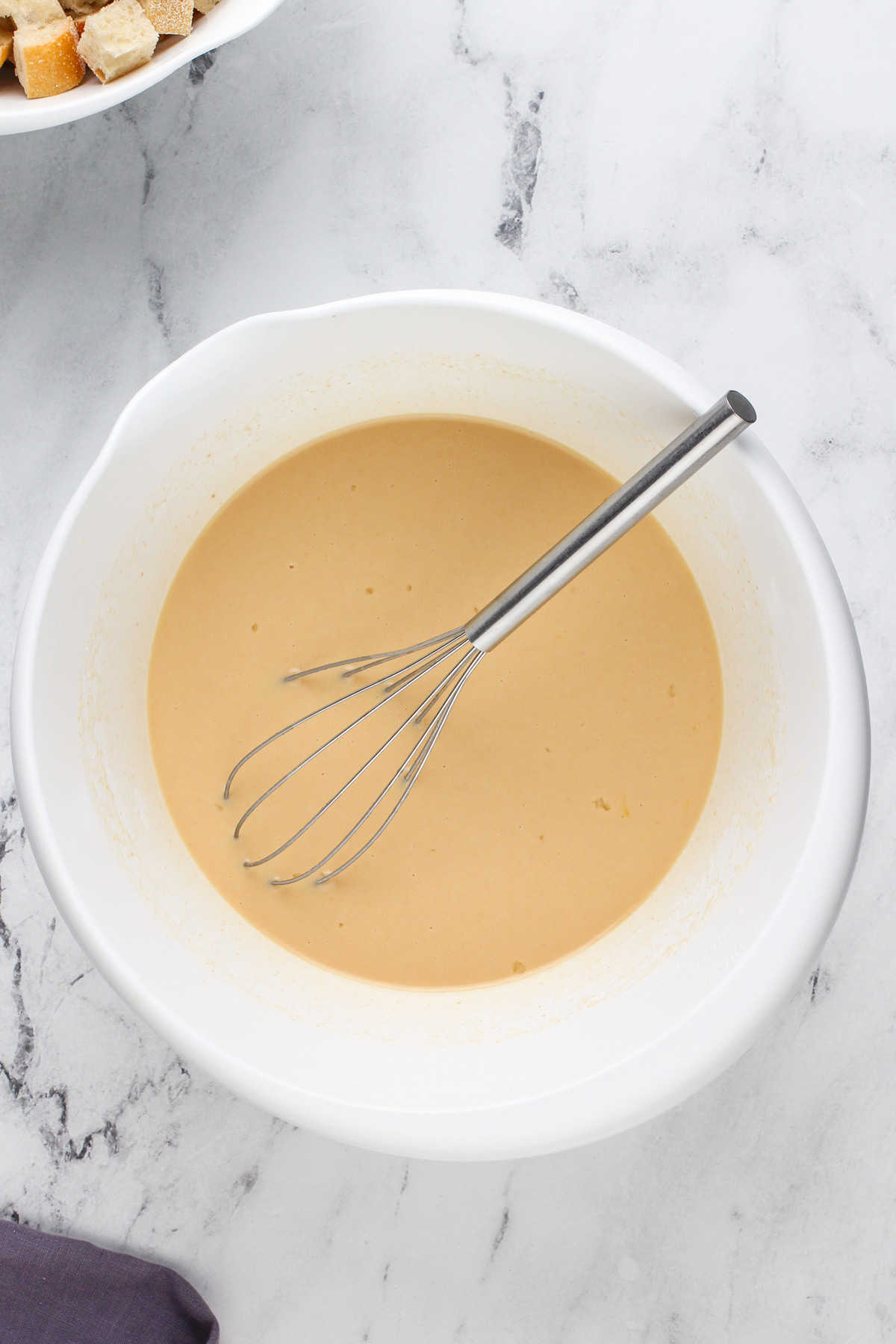 Custard for irish bread pudding whisked in a white bowl.