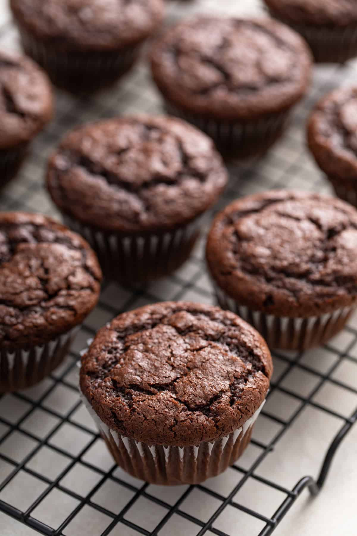 Unfrosted chocolate cupcakes made with doctored cake mix cooling on a wire rack.