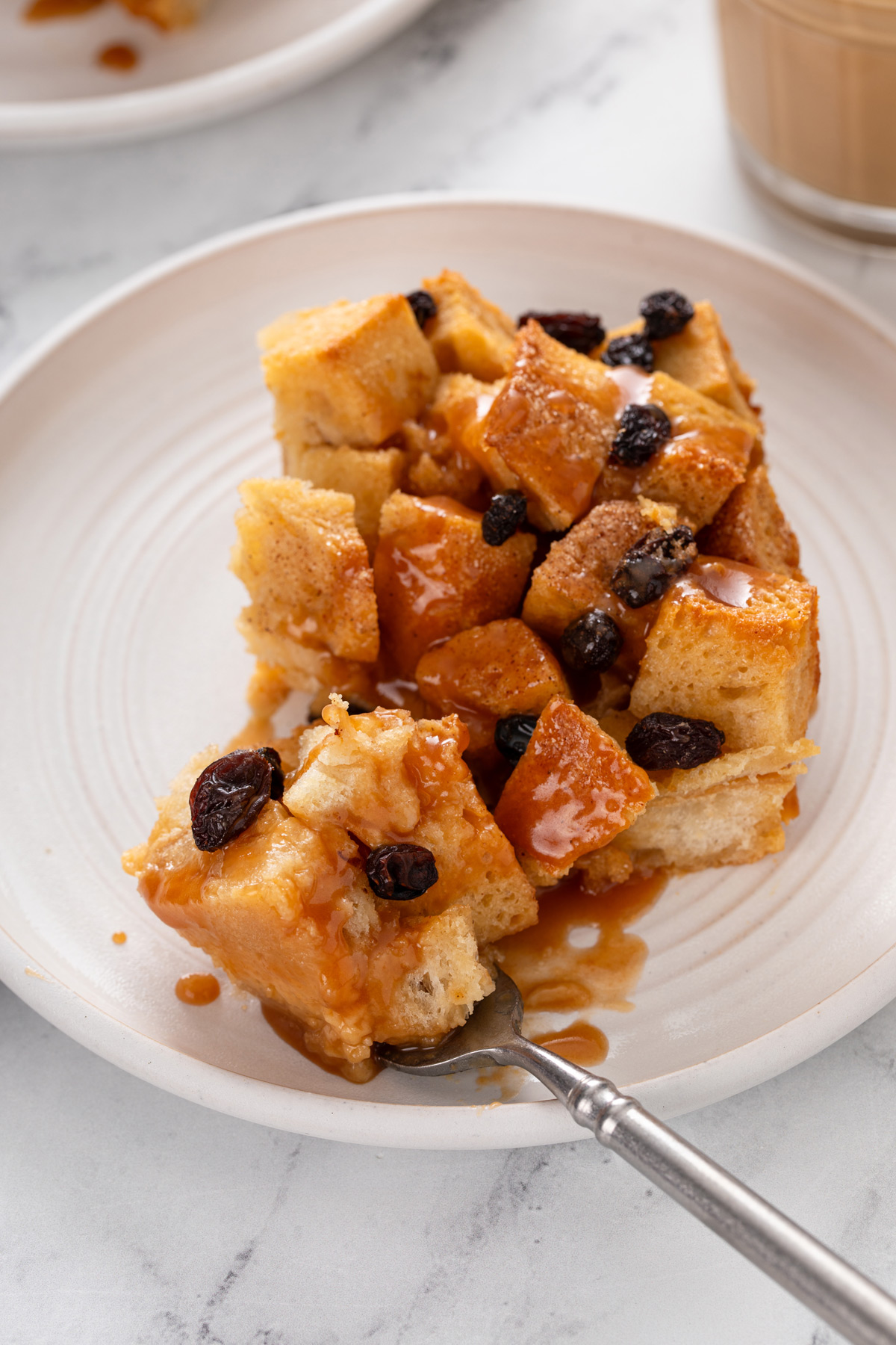 Fork cutting a bite of irish bread pudding on a plate.