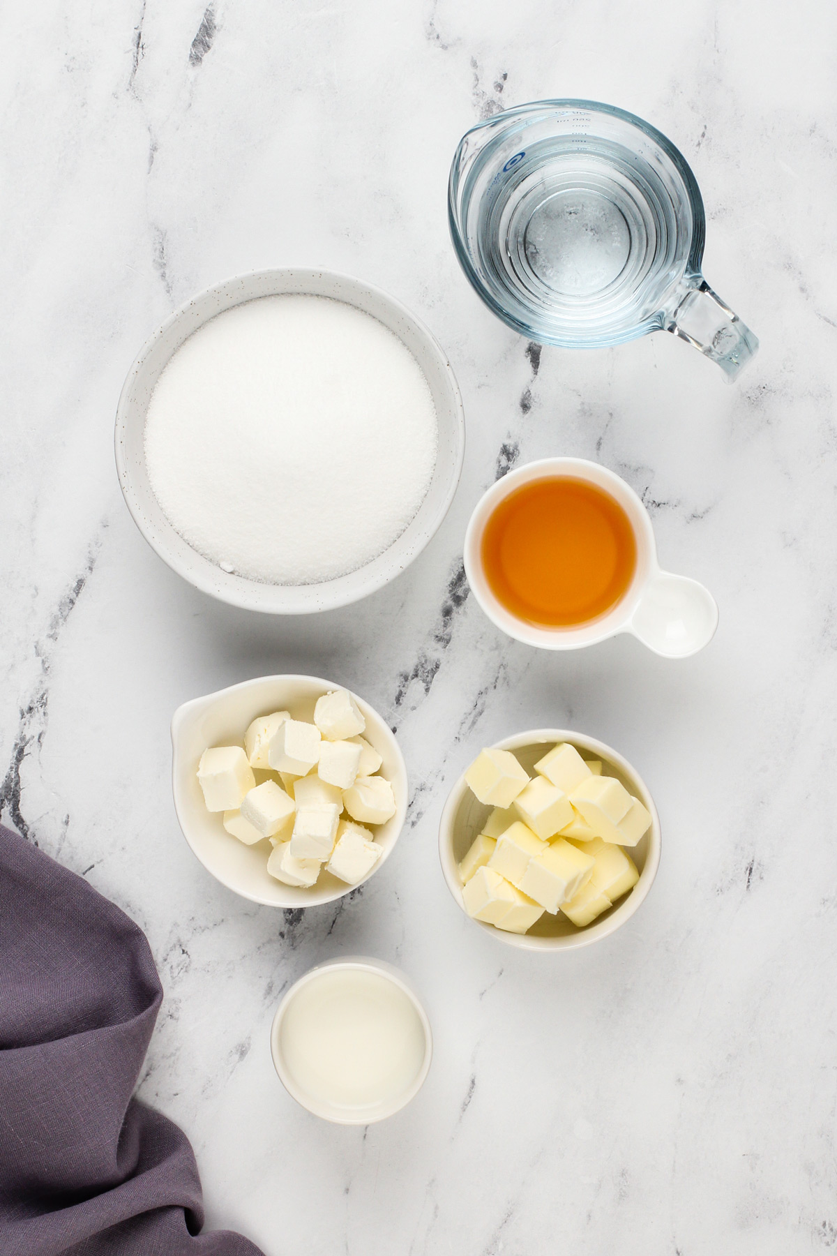 Ingredients for whiskey caramel sauce on a marble countertop.