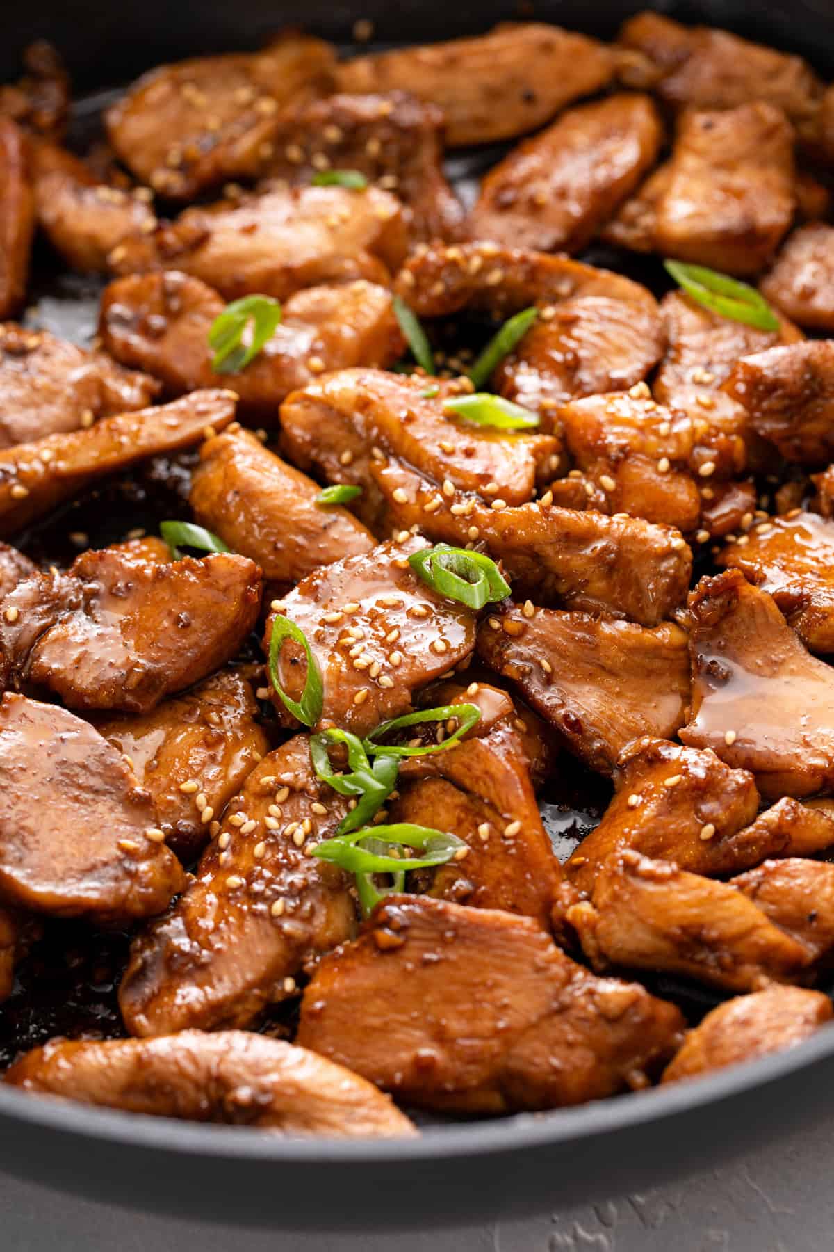 Close up of cooked honey soy chicken in a skillet.