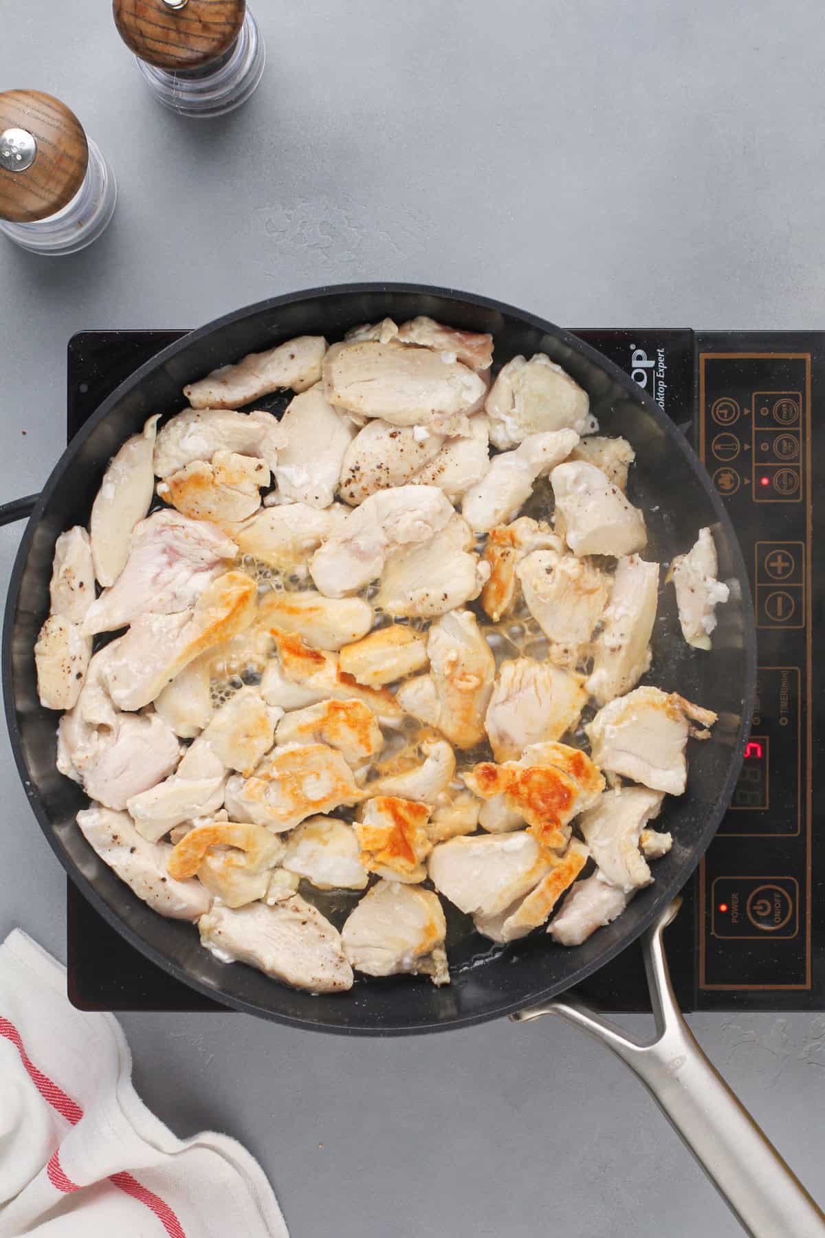 Cooking chicken in a black skillet.