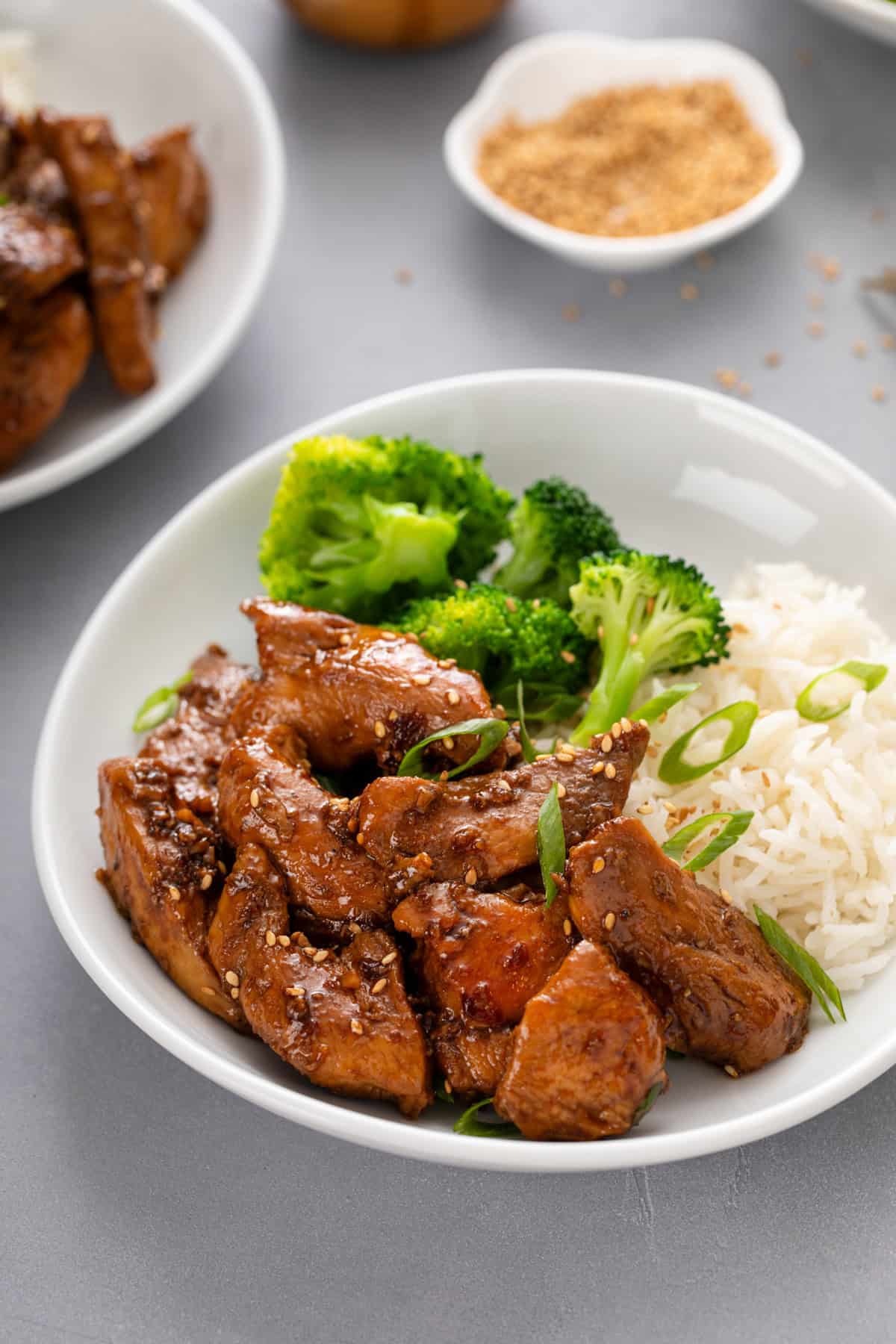 Close up of honey soy chicken, broccoli, and rice in a white bowl.