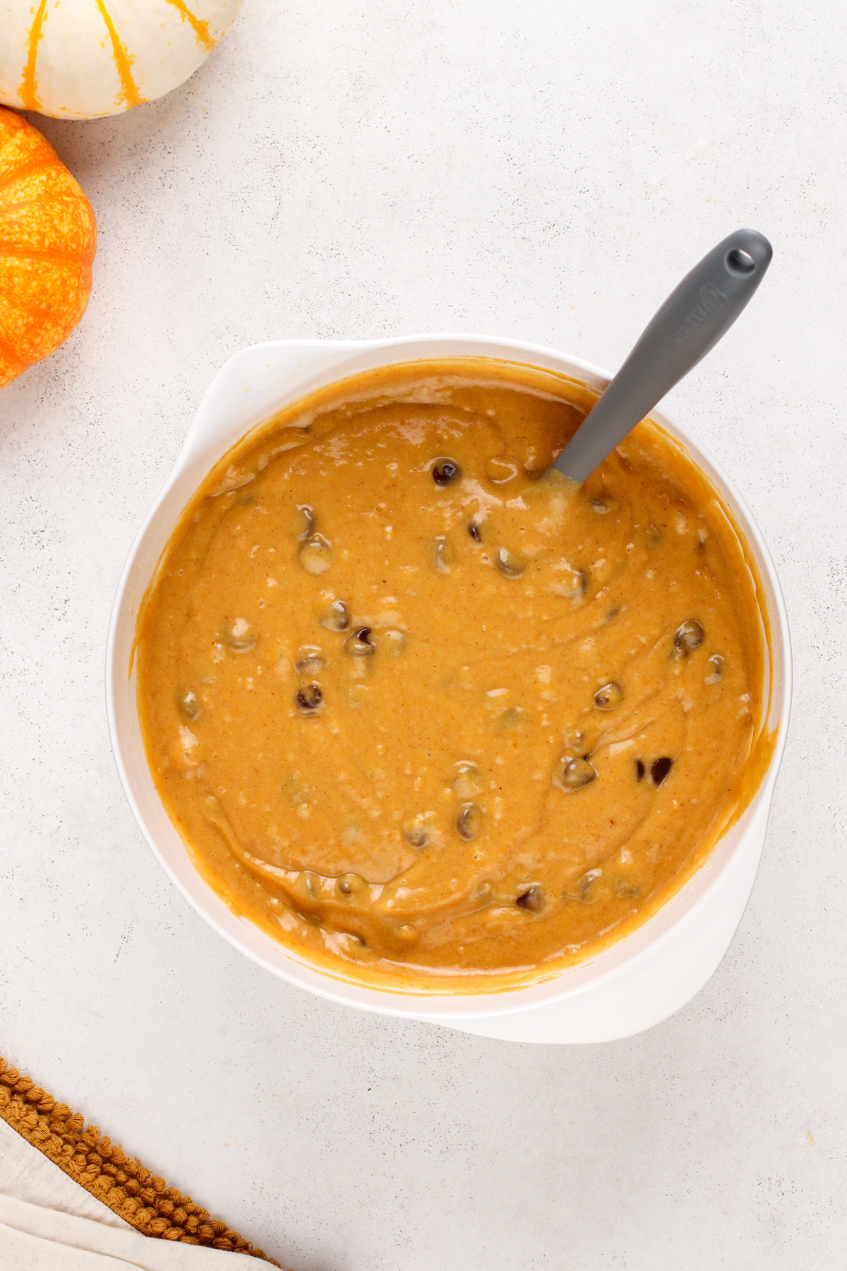 Batter for chocolate chip pumpkin bread mixed in a white bowl.