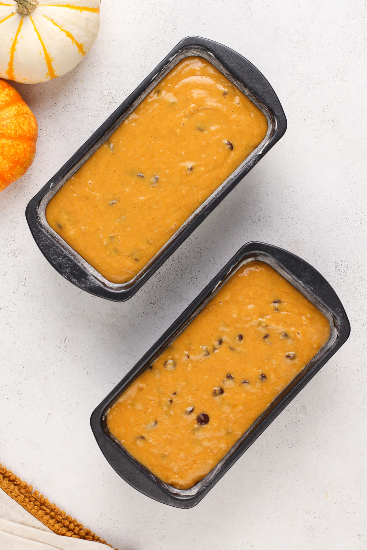 Chocolate chip pumpkin bread divided between two loaf pans, ready to go in the oven.