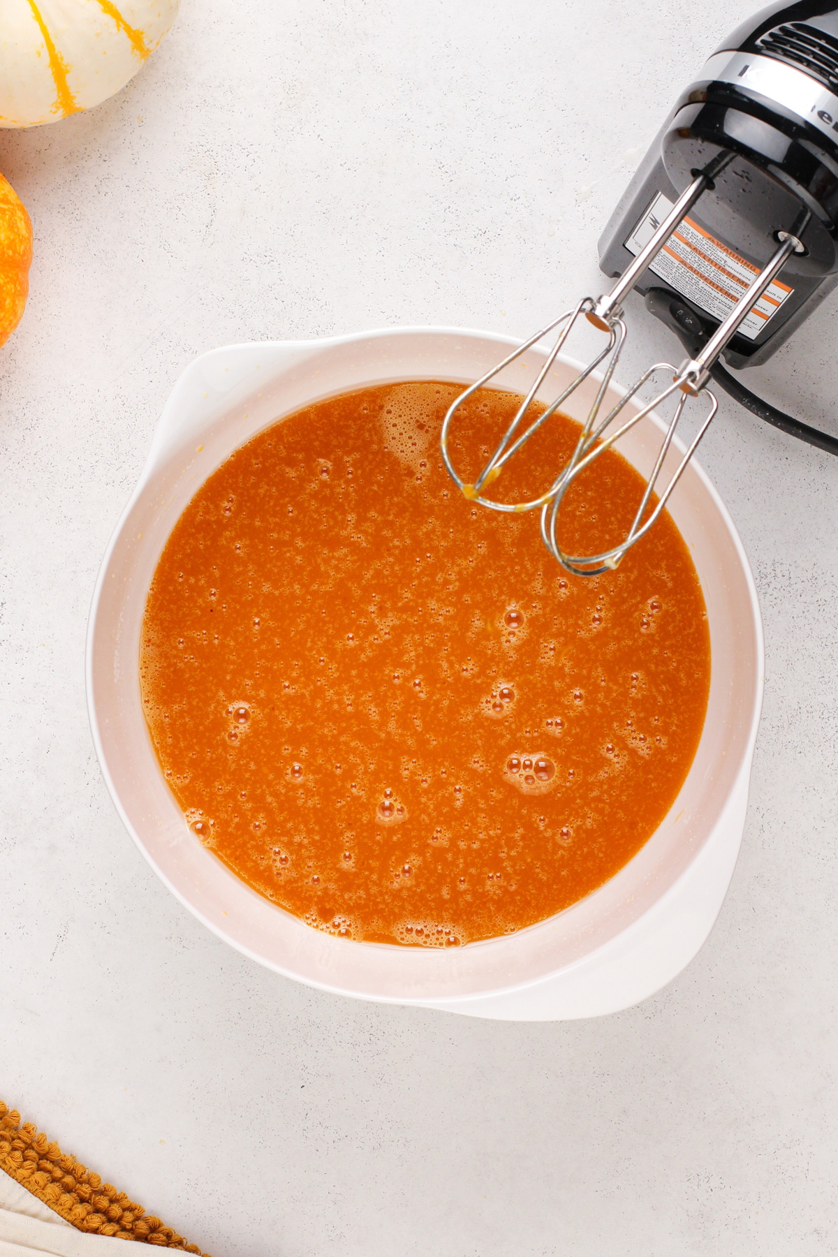 Wet ingredients for pumpkin bread mixed in a white bowl.