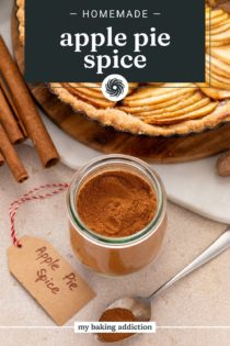 Jar of apple pie spice next to an apple tart and a tag that says "apple pie spice" on it. Text overlay includes recipe name.