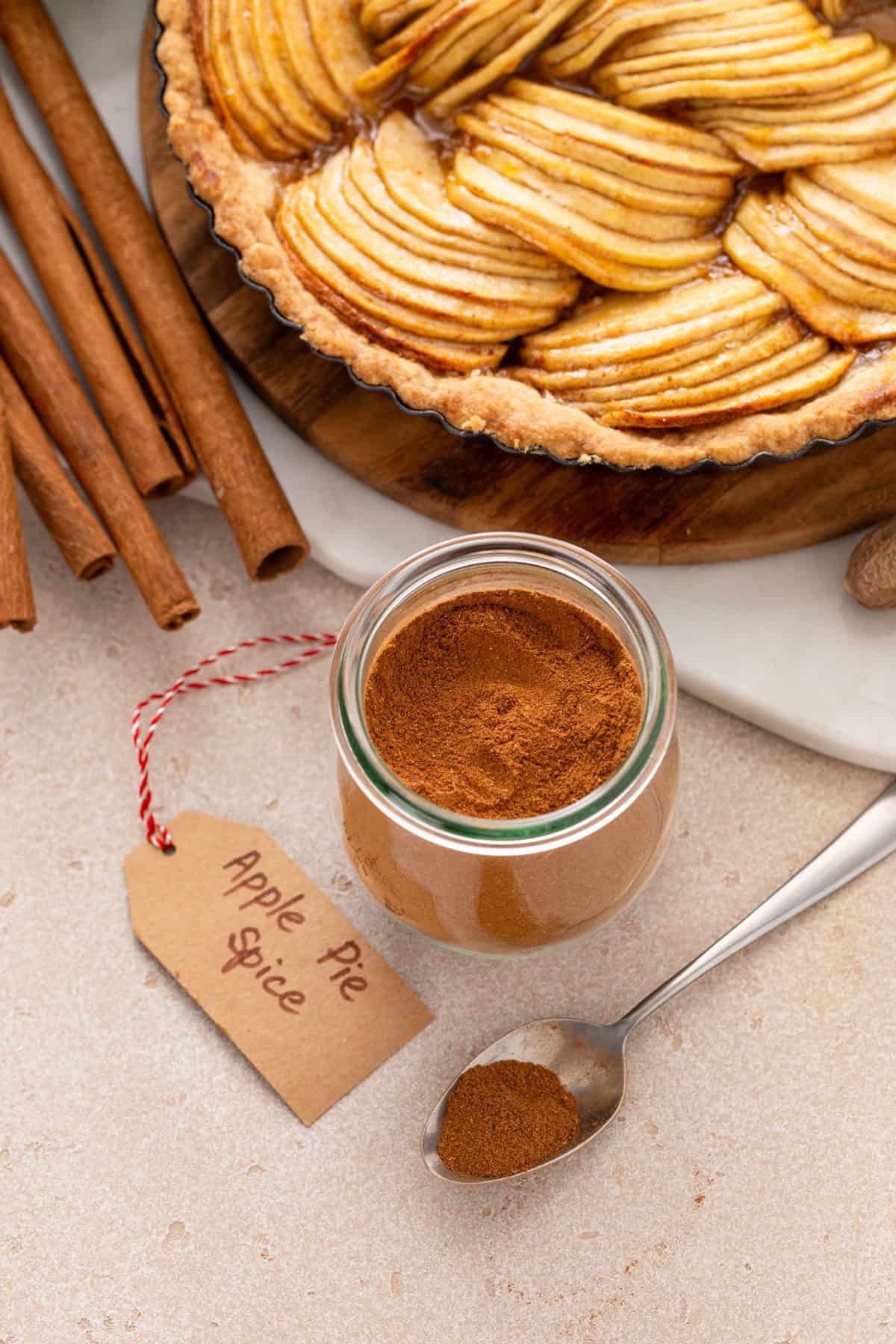 Jar of apple pie spice next to an apple tart and a tag that says "apple pie spice" on it.