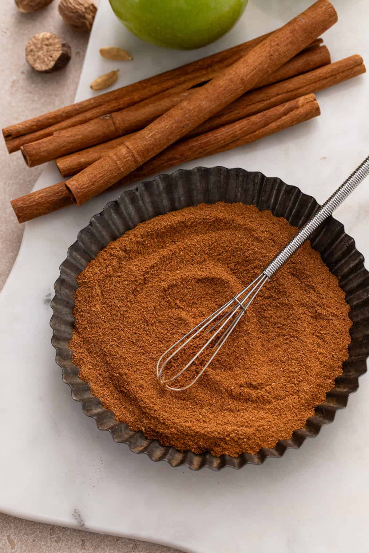 Apple pie spice being whisked together in a tart pan.