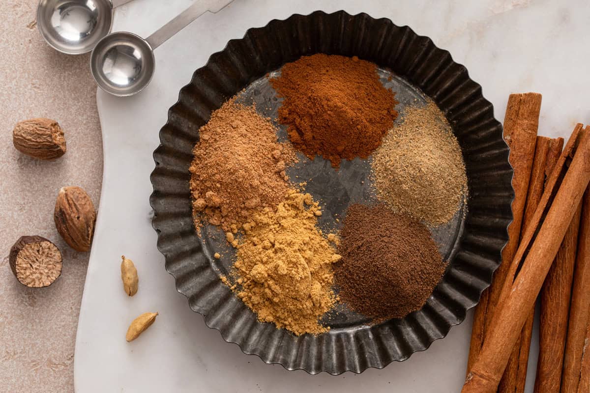 Spices for apple pie spice arranged in a tart pan.