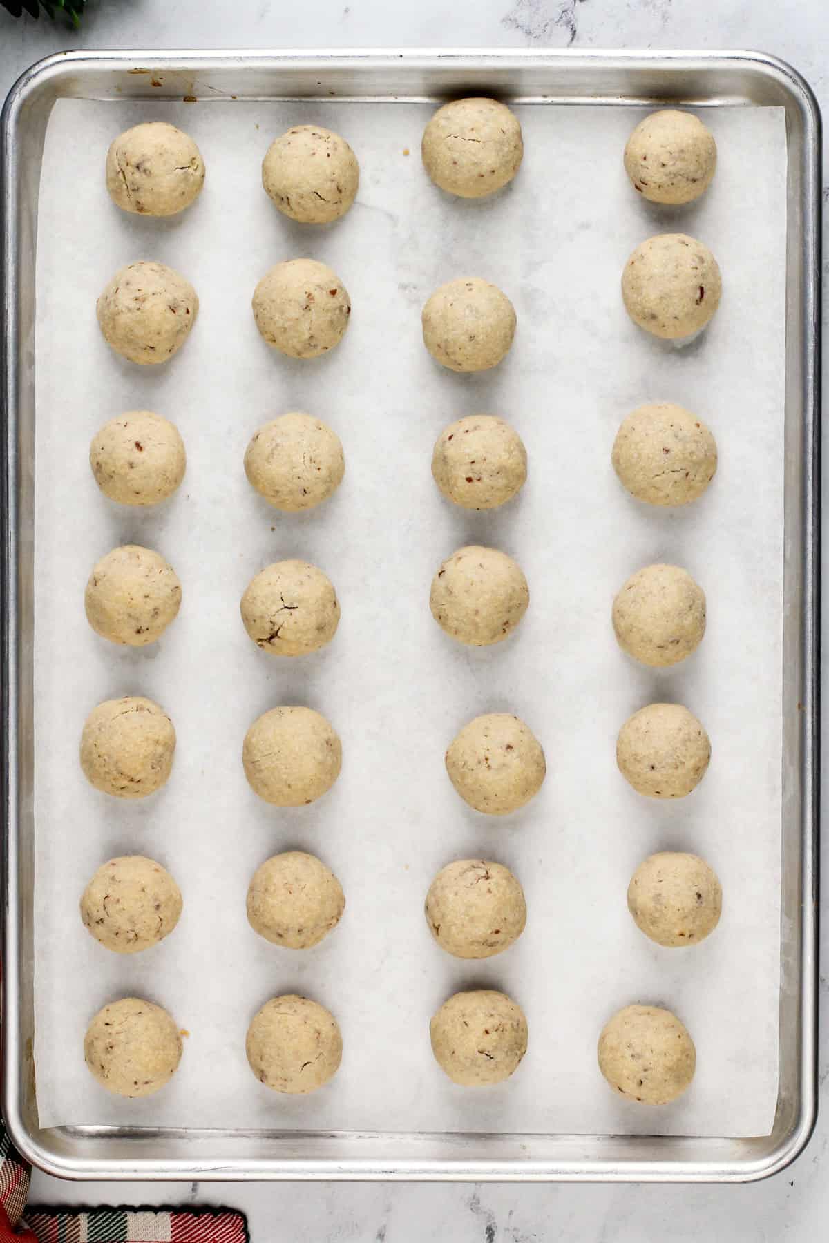 Baked snowball cookies on a lined baking sheet.