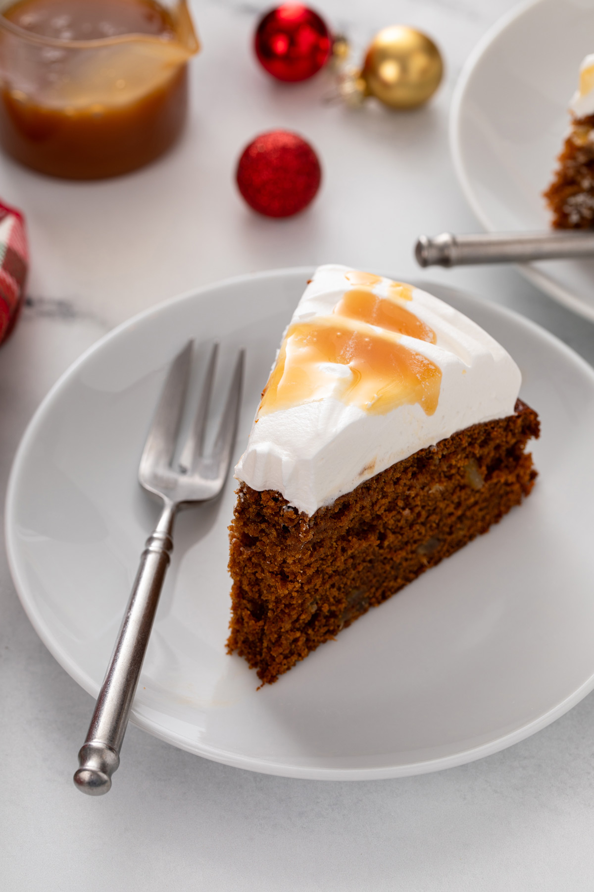 Slice of gingerbread cake with a bite taken from the end on a white plate.