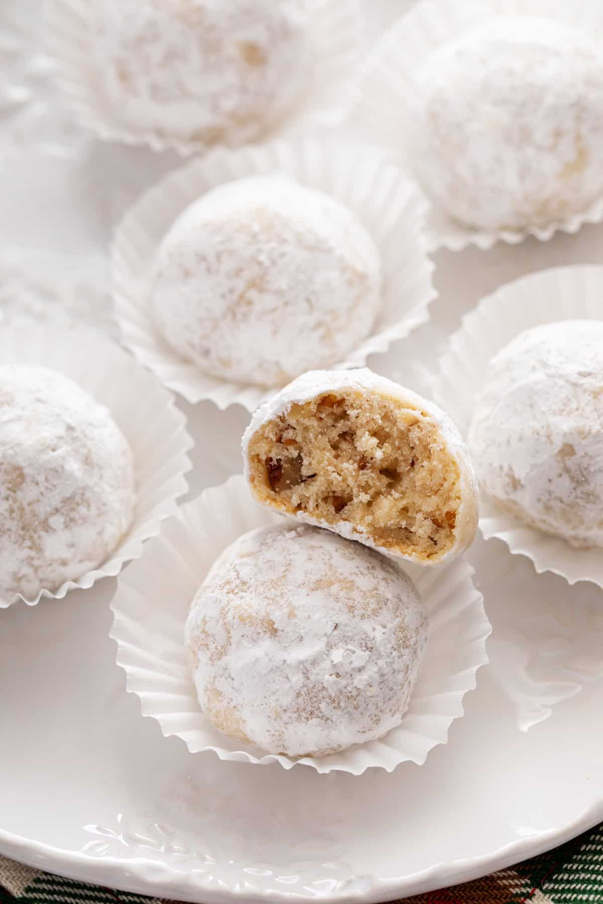 Snowball cookie with a bite taken out of it resting on top of another cookie.