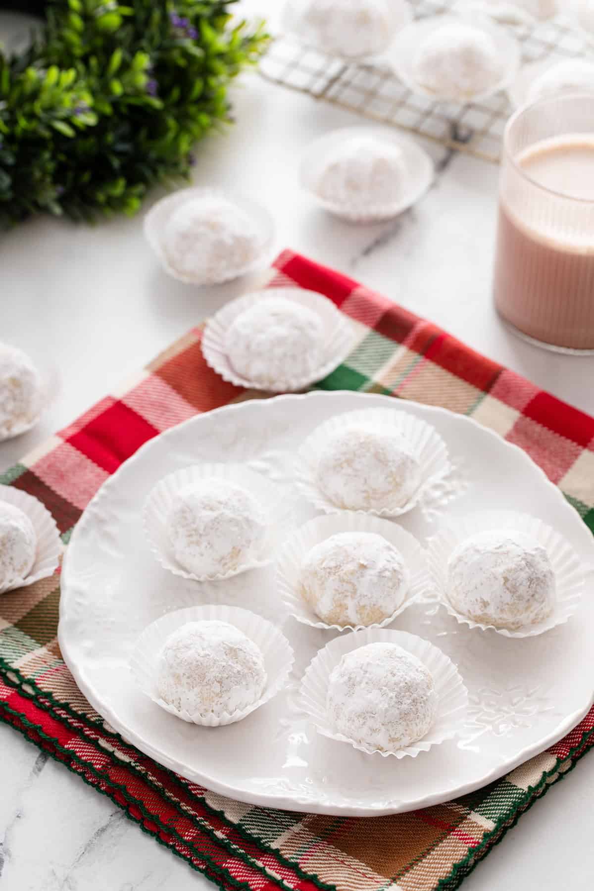 White plate filled with snowball cookies on a plaid napkin.