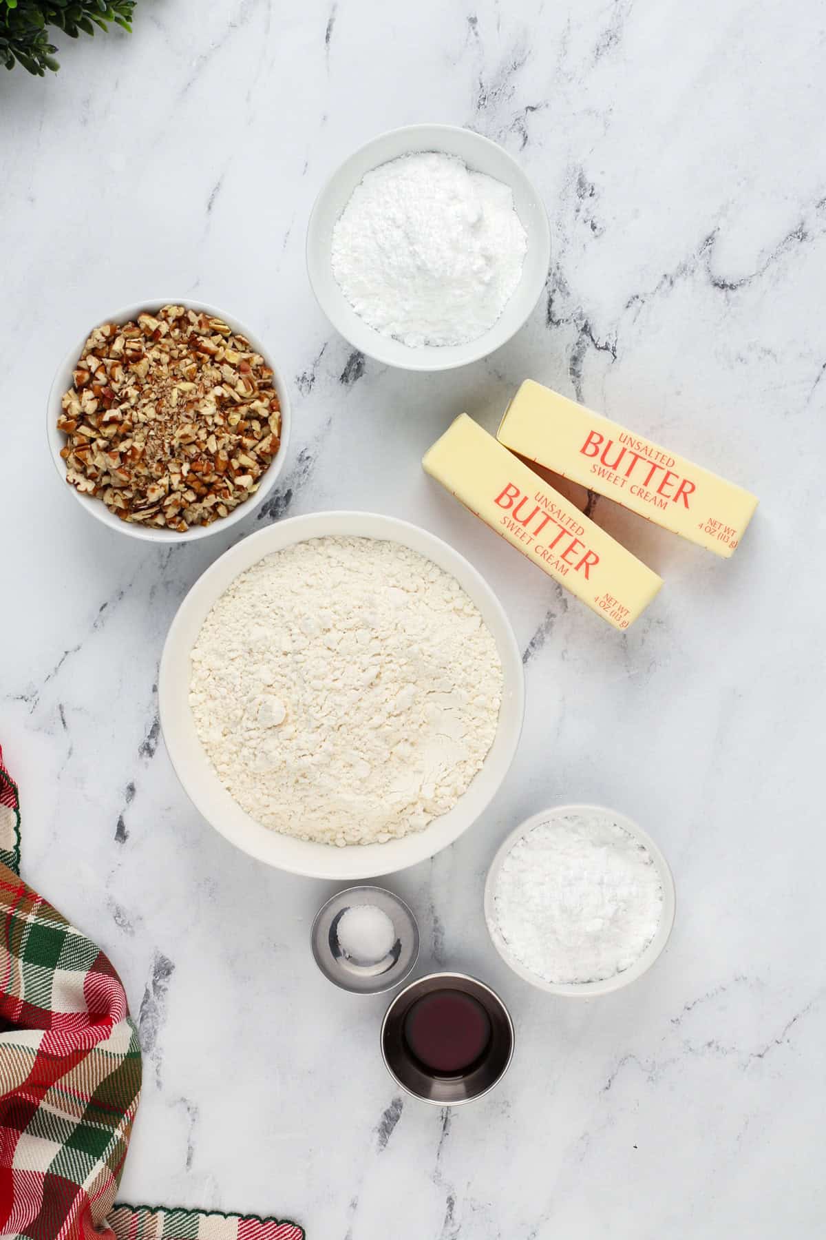 Ingredients for snowball cookies arranged on a marble countertop.