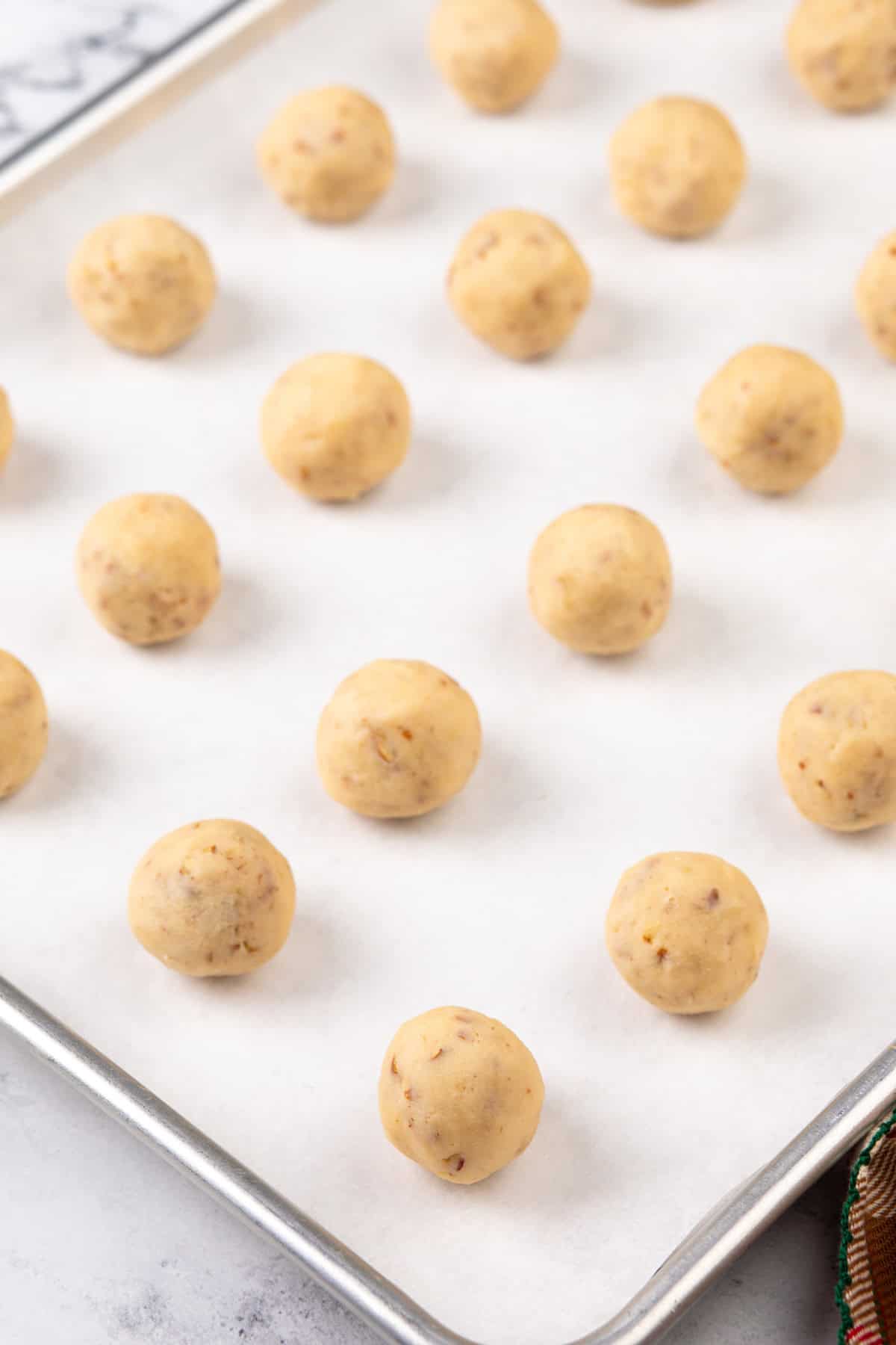 Rolls of snowball cookie dough on a baking sheet.