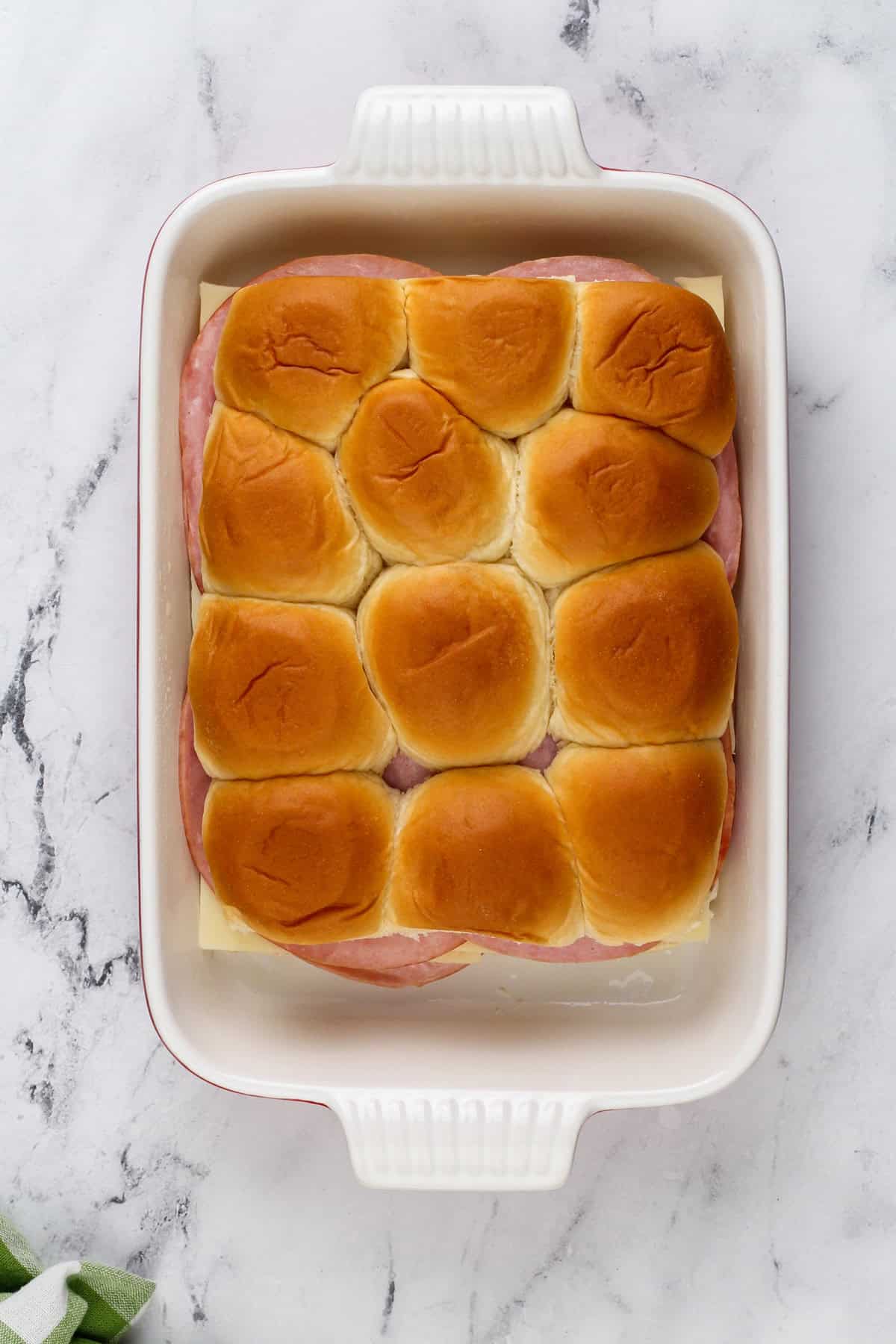 Assembled ham and cheese sliders in a baking dish.