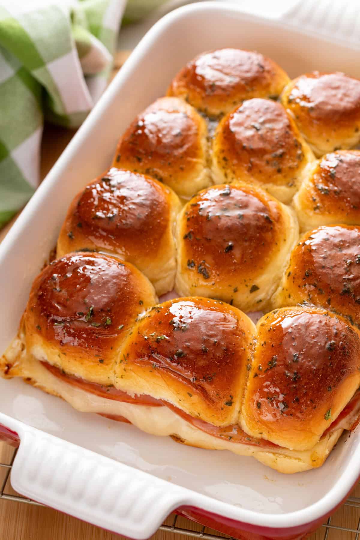 Freshly baked hot ham and cheese sliders in a ceramic baking dish.