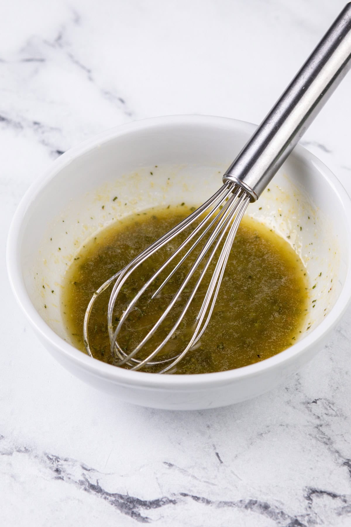 Herb butter whisked in a white bowl.