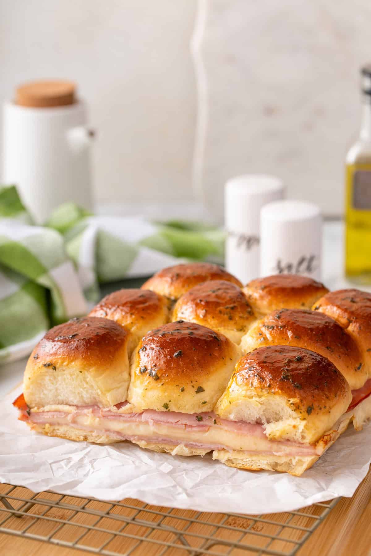 Side view of hot ham and cheese sliders on a piece of parchment paper.