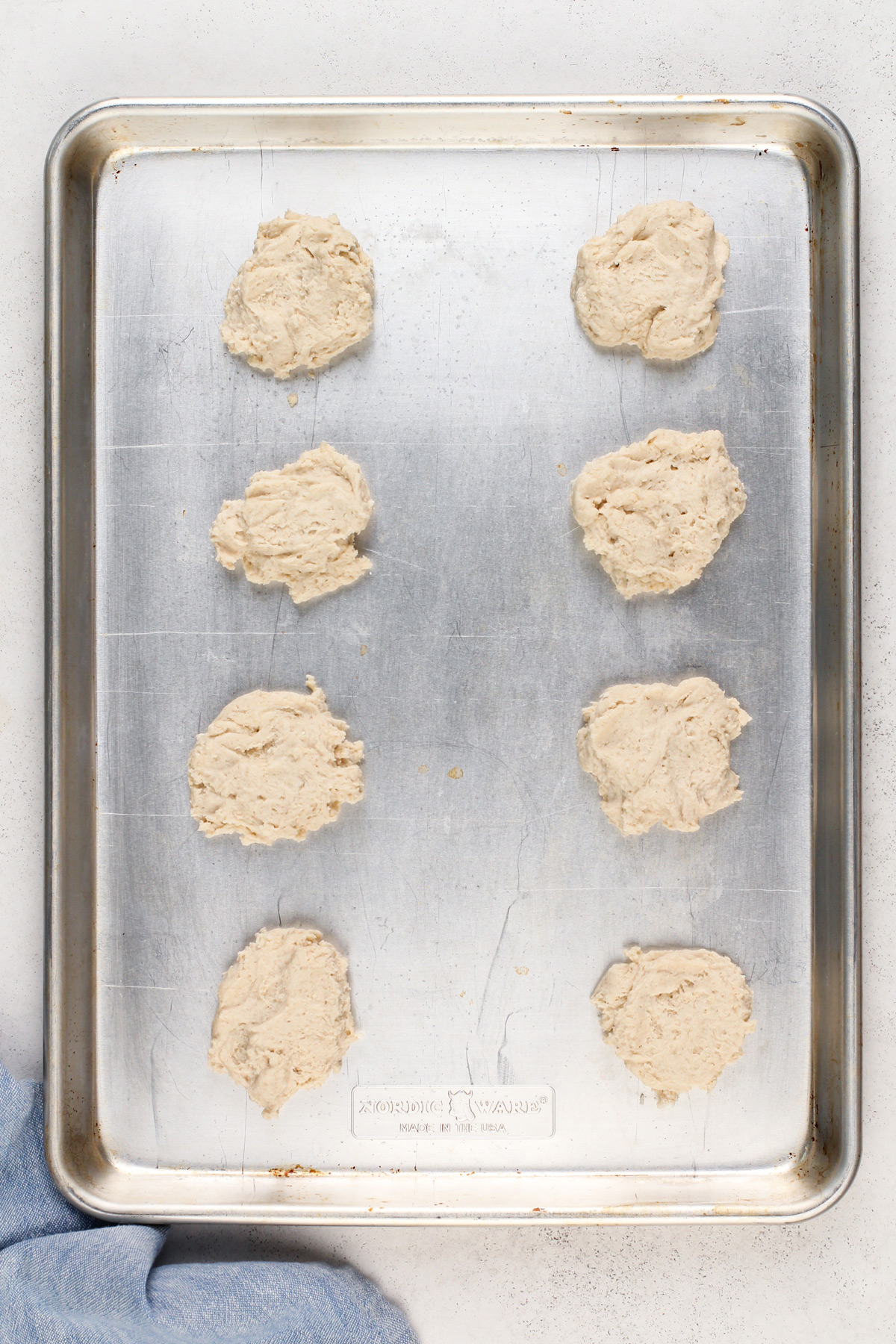 Unbaked bisquick biscuits on an unlined baking sheet.