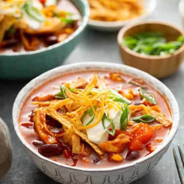 Chicken chili topped with cheese and green onions in a white bowl