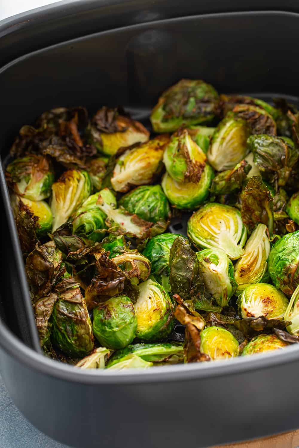 Crispy brussels sprouts fresh out of the air fryer, still in the fryer basket