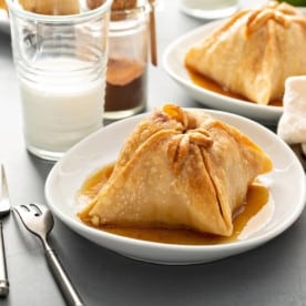 Plated old-fashioned apple dumpling with more apple dumplings in the background