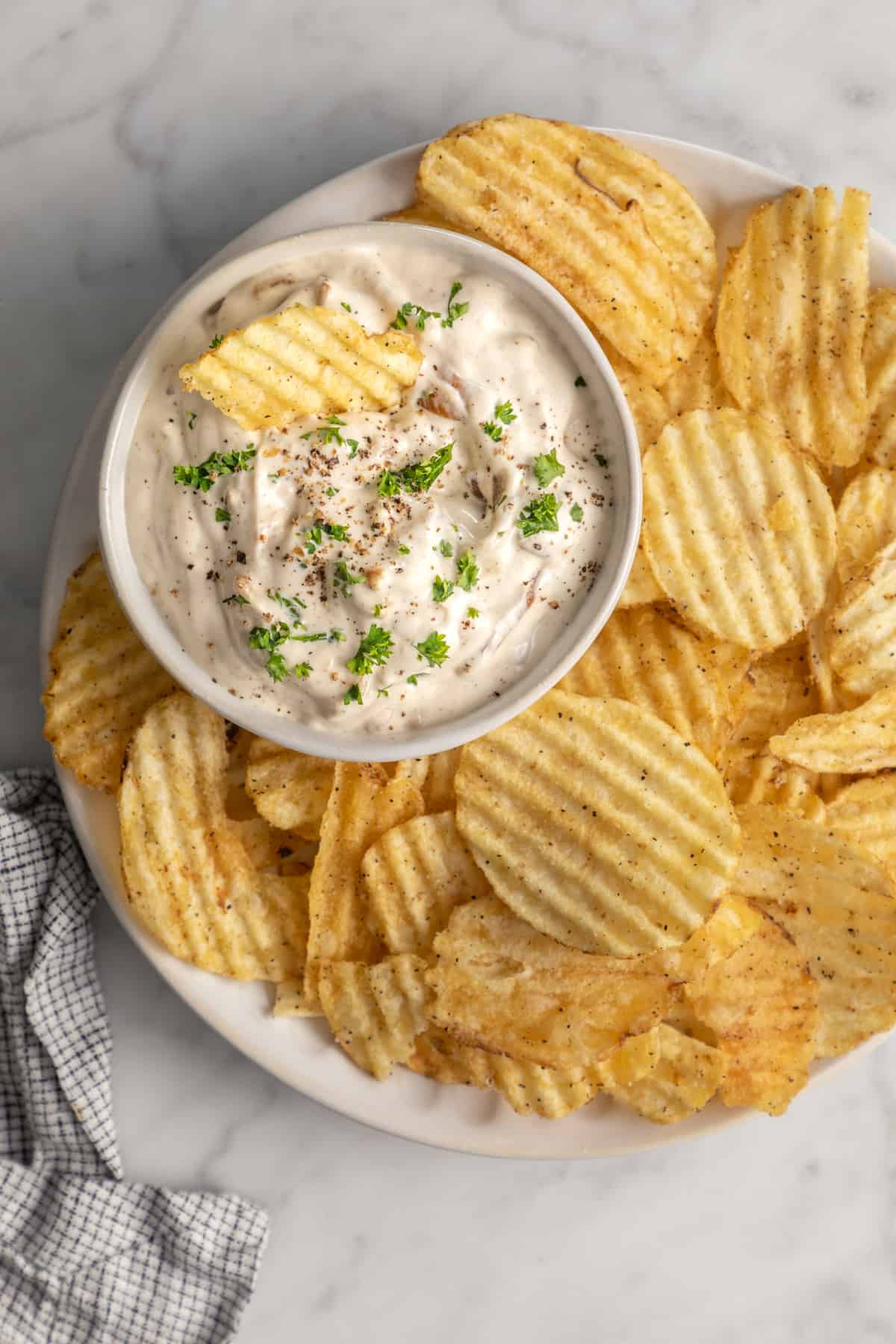 Bowl of caramelized onion dip next to potato chips.