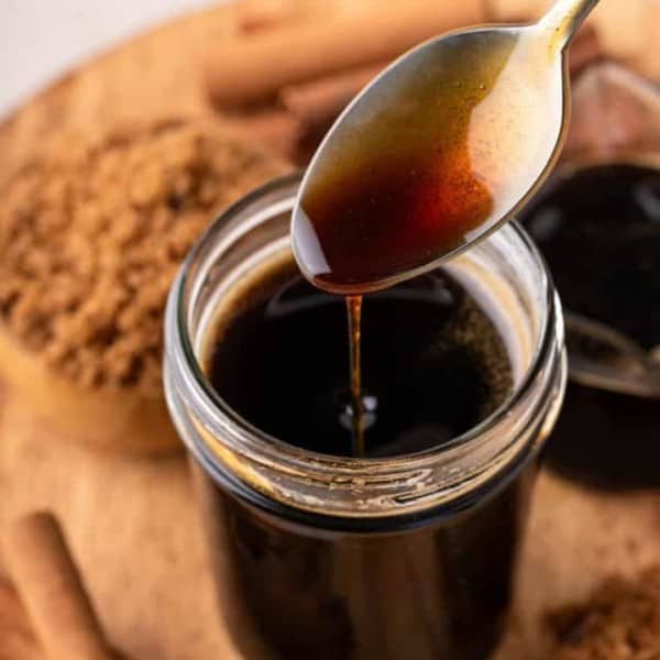 Spoon drizzling brown sugar syrup back into a jar.