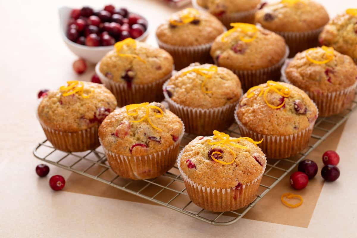 Batch of orange and cranberry muffins cooling on a wire rack.