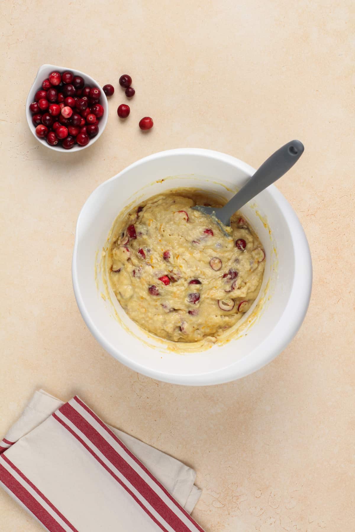 White bowl filled with cranberry orange muffin batter.