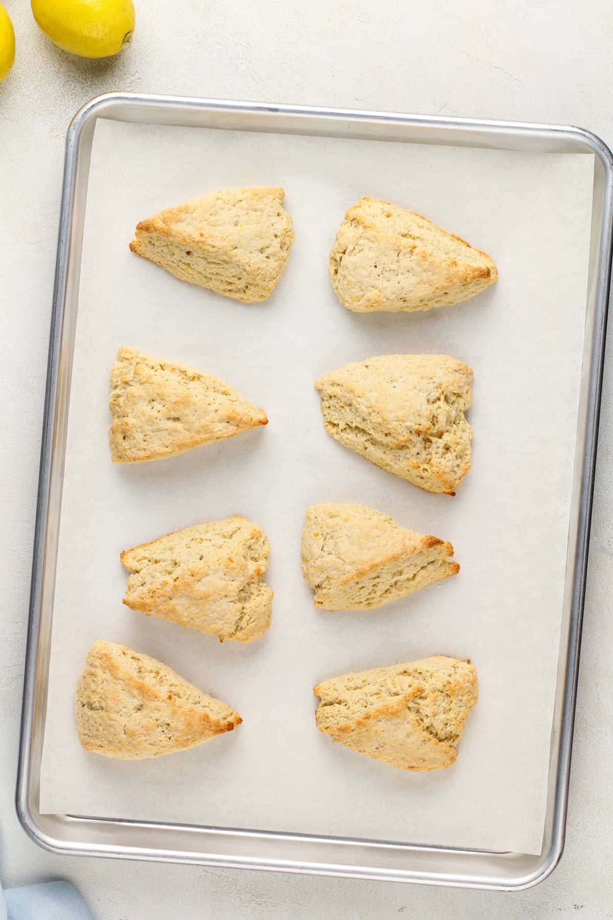 Baked lemon scones on a parchment-lined baking sheet.