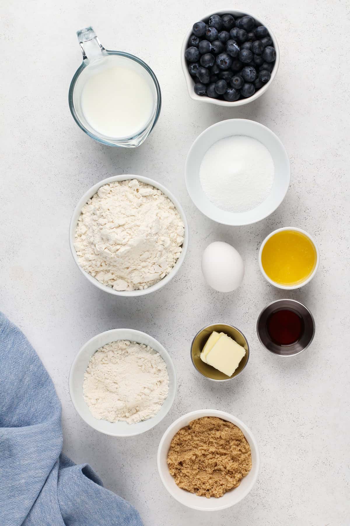 Ingredients for bisquick blueberry muffins arranged on a light-colored countertop.