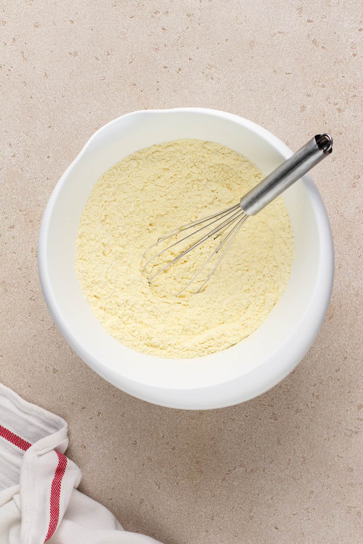 Yellow cake mix and pudding mix whisked together in a white bowl.