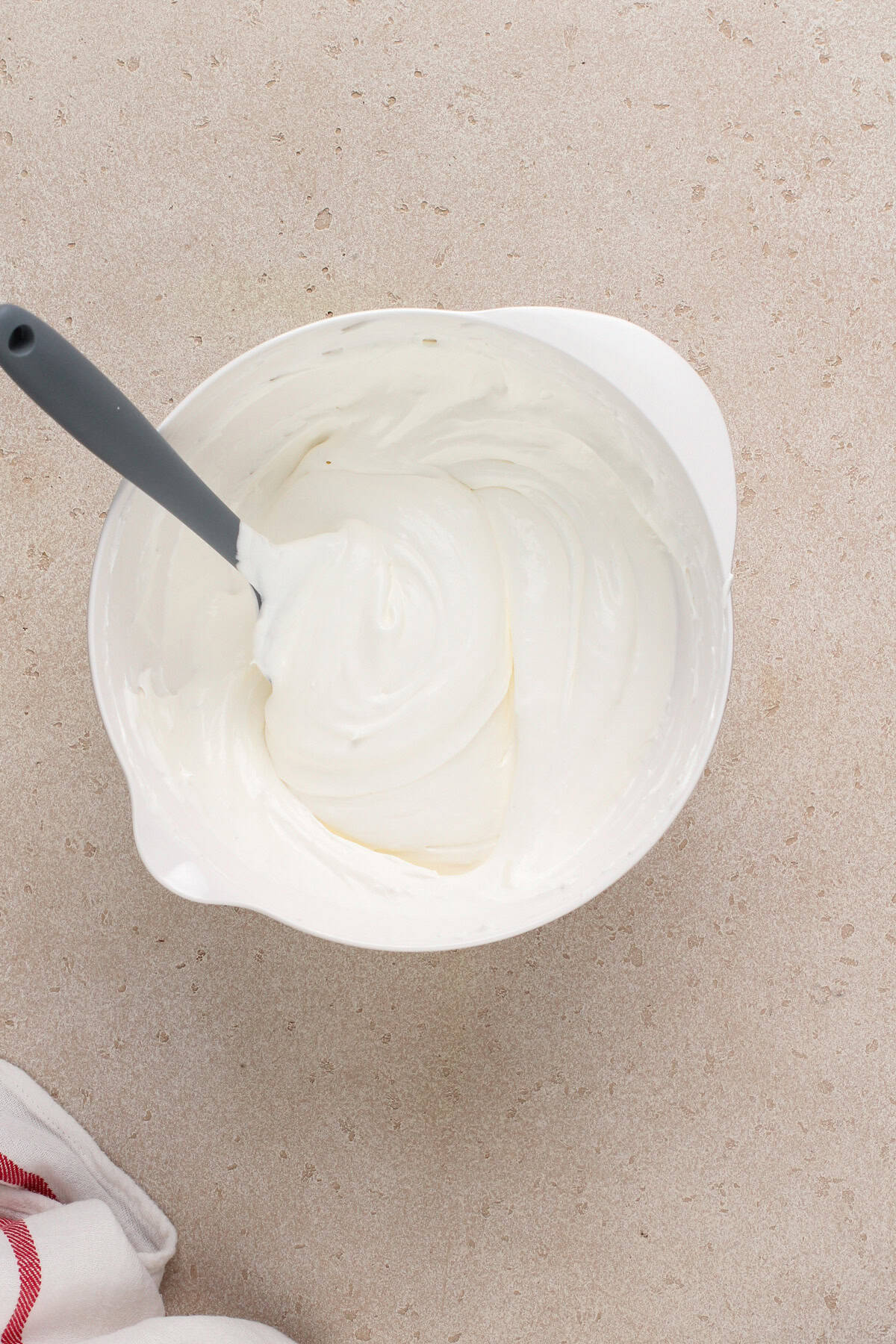 Cool whip and marshmallow fluff mixed together in a white bowl.