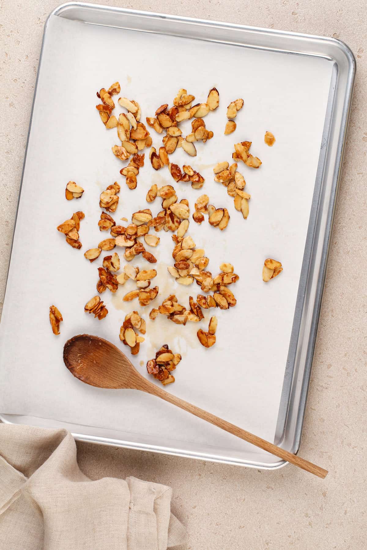 Caramelized almonds cooling on a parchment-lined baking sheet.