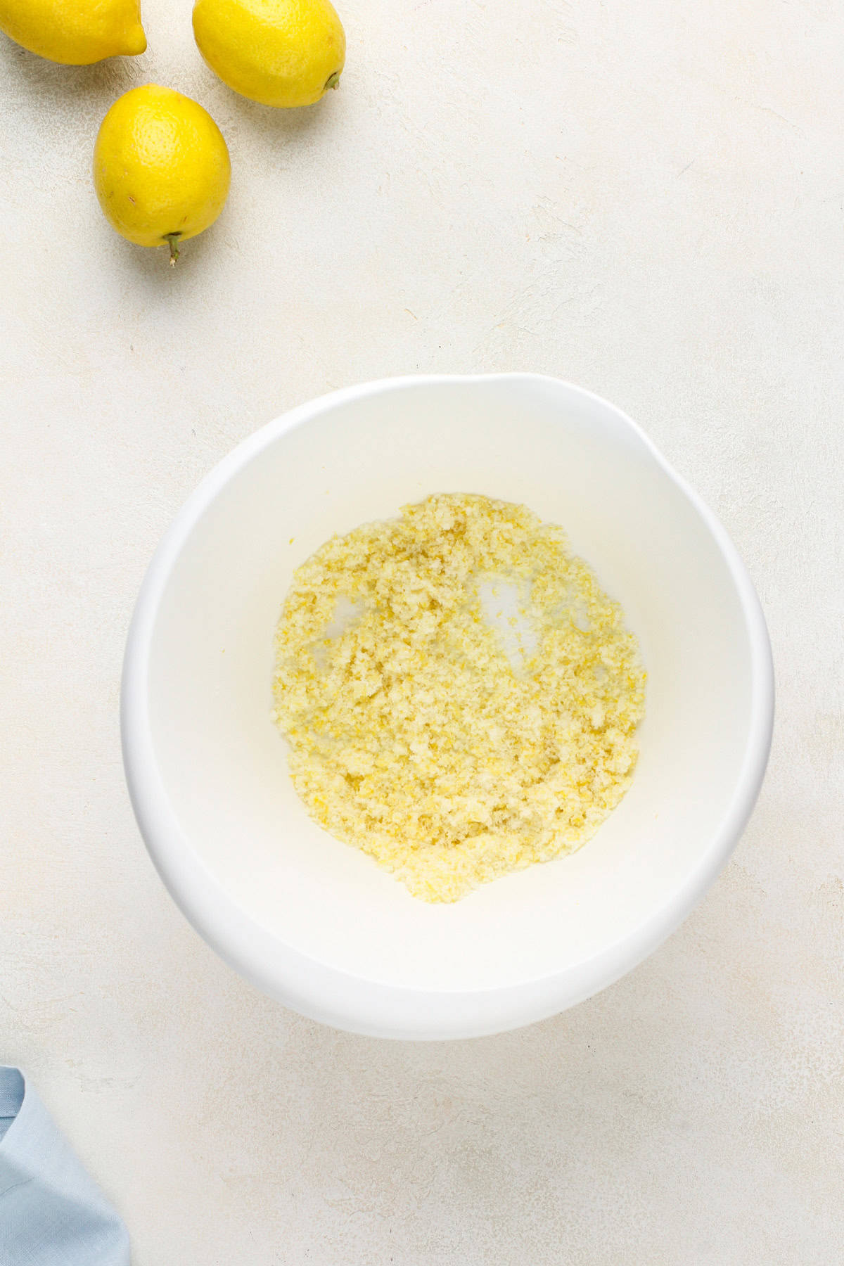 Lemon zest combined with sugar in a white bowl.