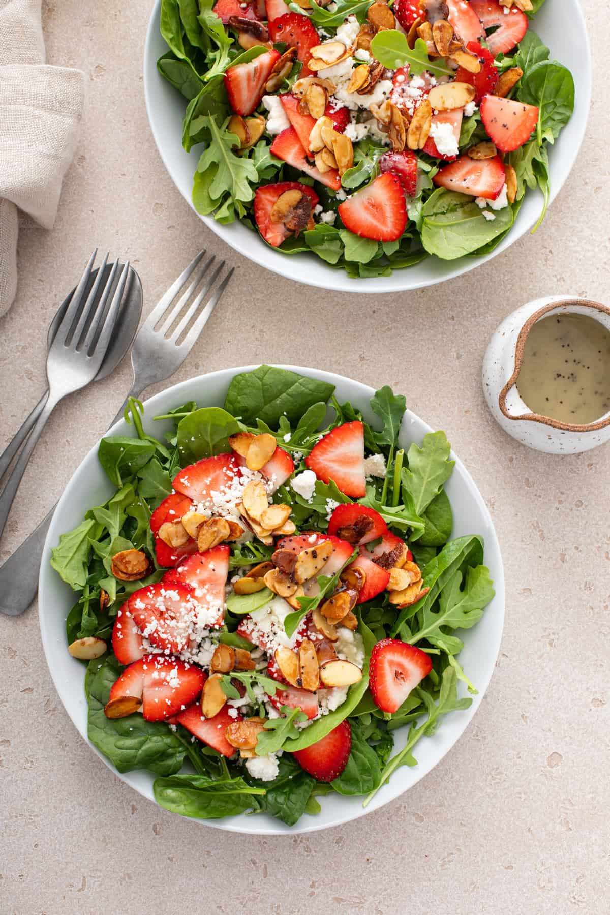 Overhead view of two bowls of strawberry salad topped with poppy seed dressing.