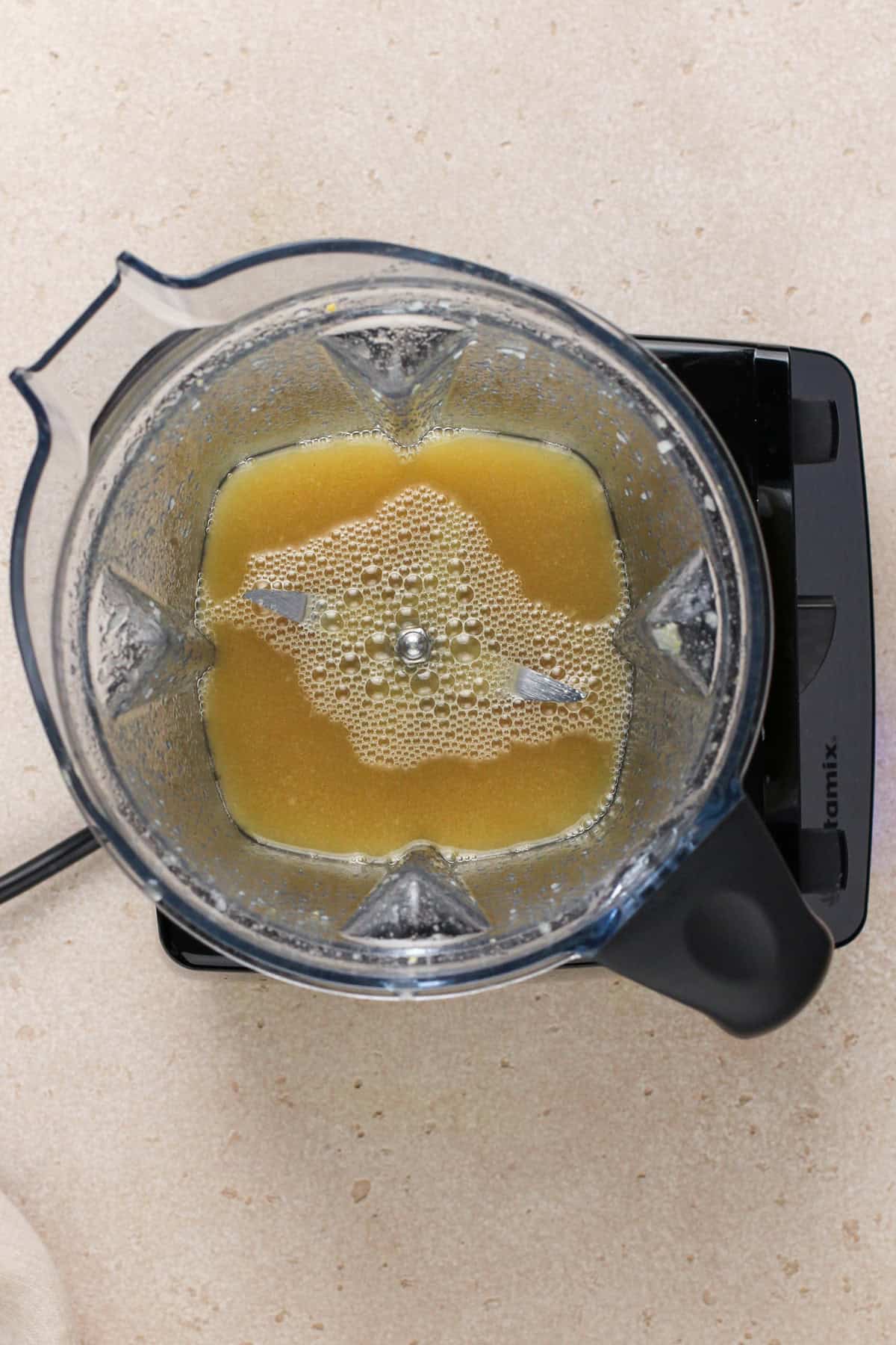 Sugar, vinegar, and mustard blended together in the bowl of a blender.