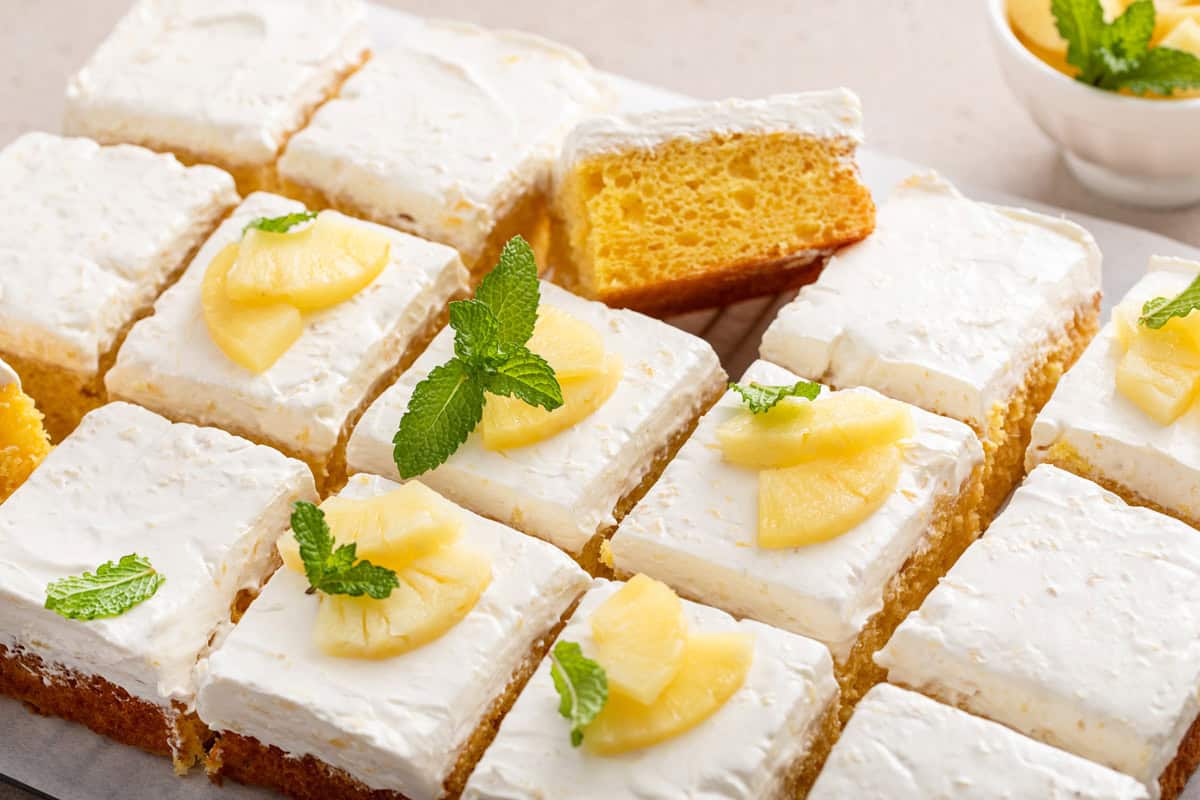 Sliced easy pineapple cake garnished with fresh mint and pieces of pineapple.