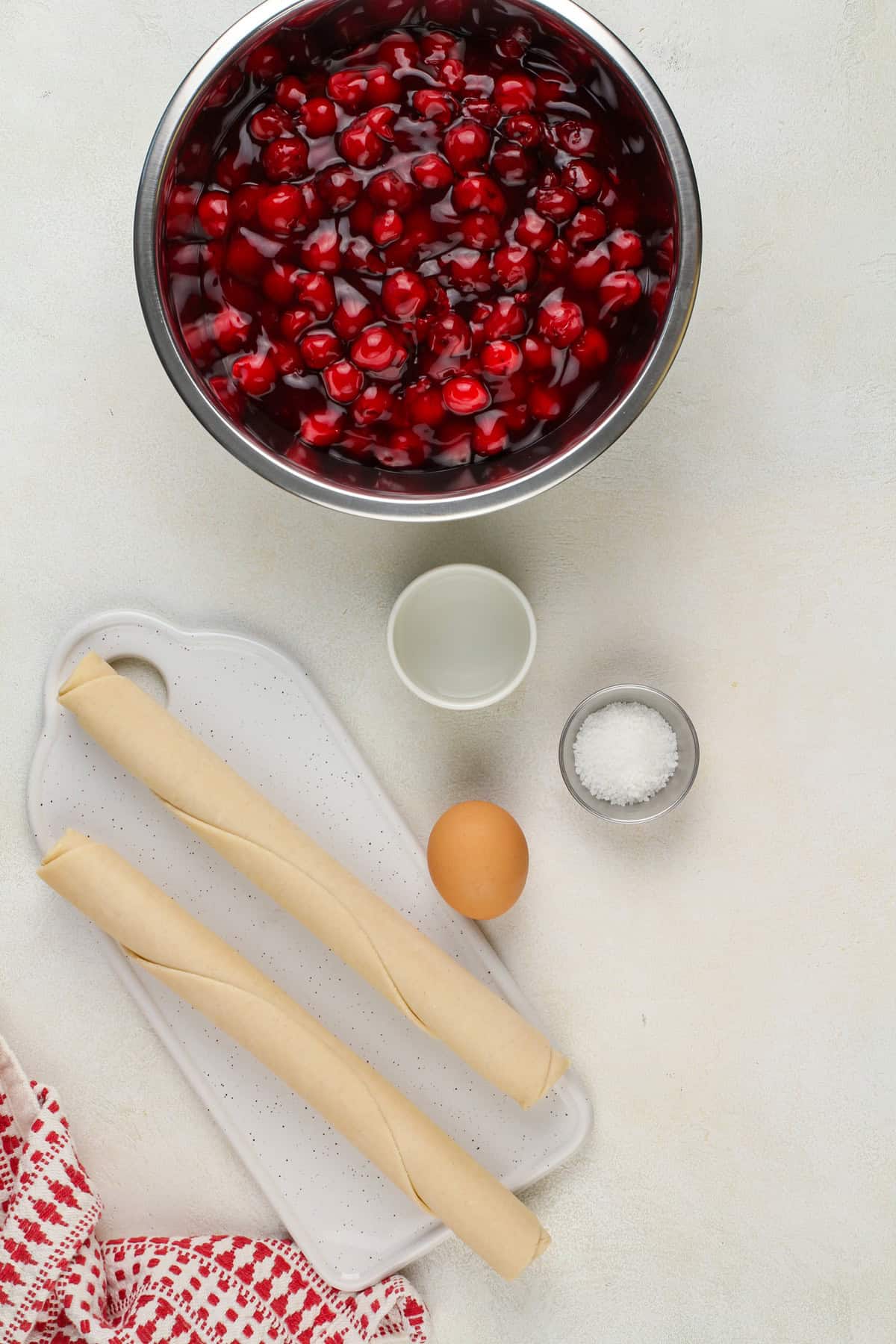 Ingredients for sour cherry pie arranged on a beige countertop.